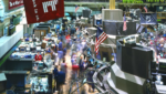 The busy trading floor of the New York Stock Exchange, with traders among banks of screens and an American flag hanging overhead